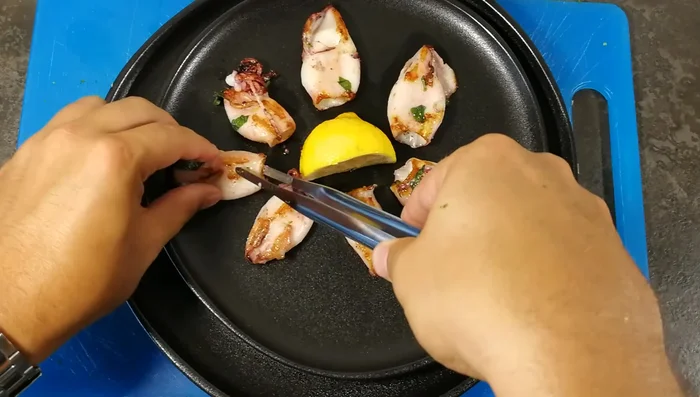 Posizionate i calamari cotti su un piatto con una fetta di limone al centro.