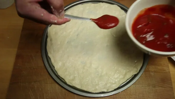 Aggiungere la salsa di pomodoro sull'impasto, coprendo tutta la superficie. Aggiungere basilico se desiderato.