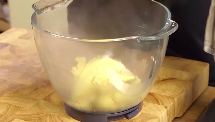 Trasferire l'impasto in una ciotola ampia e, usando un robot da cucina, farlo girare per abbassare leggermente la temperatura. (61.86)