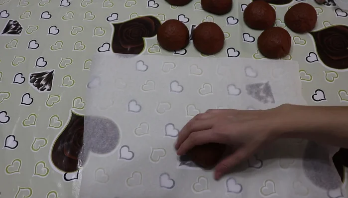 Forma delle palline con ogni pezzo e stendile con un mattarello su carta da forno (407.81).