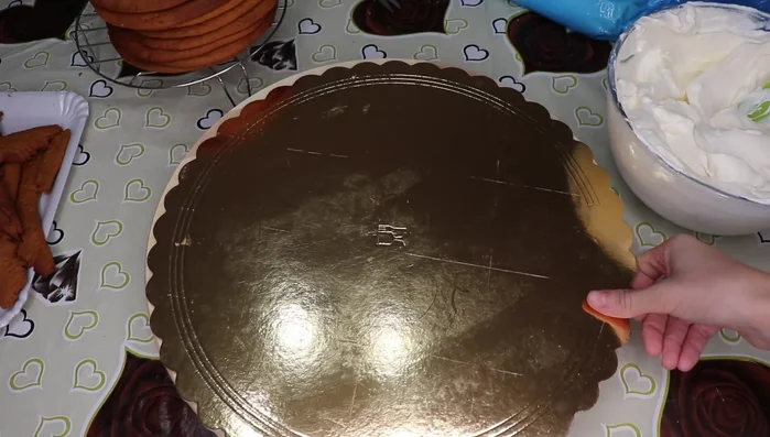 Assembla la torta: disponi uno strato di biscotti, uno strato di crema e ripeti fino ad esaurimento ingredienti, lasciando un disco da parte per la decorazione (722.289).