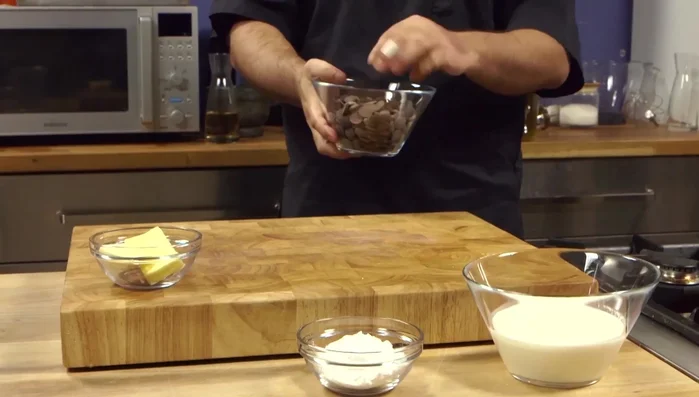Preparare la glassa al cioccolato: sciogliere il cioccolato fondente, aggiungere la panna bollente e mescolare.
