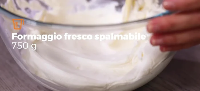 In una ciotola capiente, unire il formaggio cremoso e lo yogurt greco, amalgamare bene. Aggiungere il miele intiepidito e mescolare nuovamente.