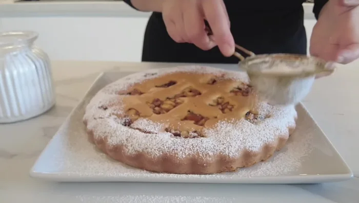 Una volta cotta, lasciar raffreddare la crostata prima di spolverizzare con zucchero a velo e servire.