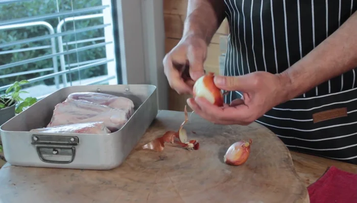 Aggiungere la cipolla tagliata grossolanamente (togliere le foglie esterne, lasciando l'ultima leggermente gialla), sale, pepe abbondante e olio d'oliva. Strofinare bene il tutto sugli stinchi a mani nude.