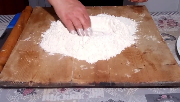 Creare una fontana con la farina sulla spianatoia.