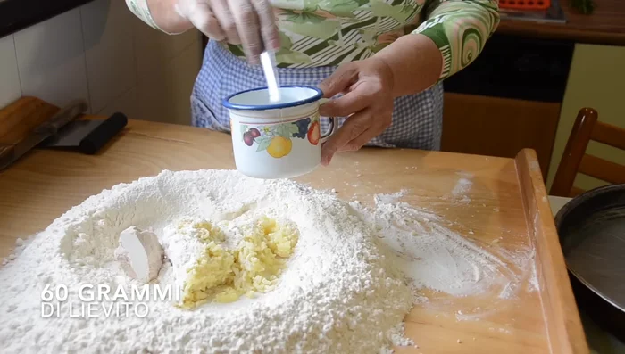 Aggiungere il lievito, il sale, lo zucchero, l'olio e il latte tiepido nella fontanella (140.459)