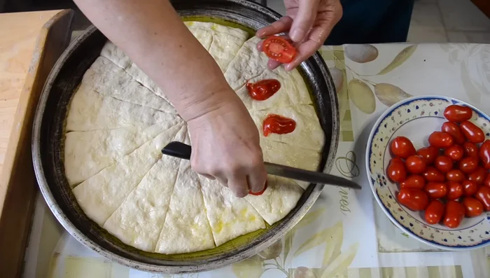 Per la focaccia con i pomodorini, stendere l'impasto e condire con pomodorini, origano, sale, olio e basilico (617.25)