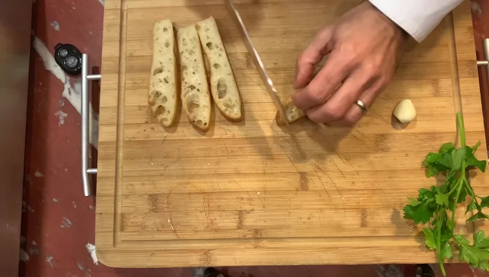 Nel frattempo, preparate le bruschette: tagliate a fette la focaccia, tostatela in padella e strofinatela con uno spicchio d'aglio per intensificare il profumo.