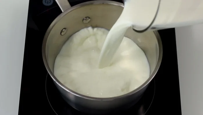 Versiamo il resto del latte (1 litro in totale) in un pentolino e scaldiamo a fiamma media. Aggiungiamo la polpa e la bacca di vaniglia, portando a ebollizione.