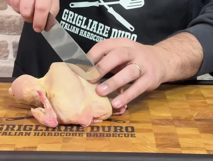 Aprire il pollo: Usare forbici o coltello per aprire il pollo a libro, tagliando il petto in due. Rimuovere le alette (possono essere usate per il brodo).