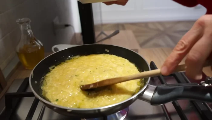 Cuocete la frittata a fiamma bassa, senza coperchio, muovendola delicatamente per farla rapprendere uniformemente (come mostrato nel video).