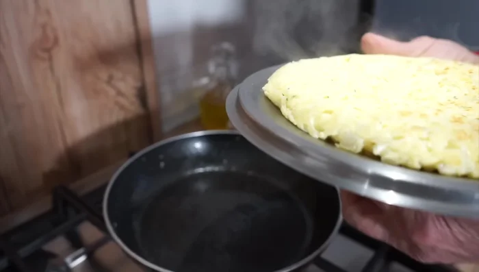 Quando la frittata è quasi cotta, giratela delicatamente per farla cuocere dall'altro lato.