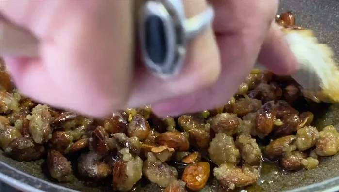 Continuare a mescolare fino a quando lo zucchero si scioglie e le mandorle iniziano a caramellare.