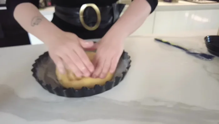 Imburrate uno stampo per crostata e versate l'impasto, stendendolo con le mani dal centro verso l'esterno.