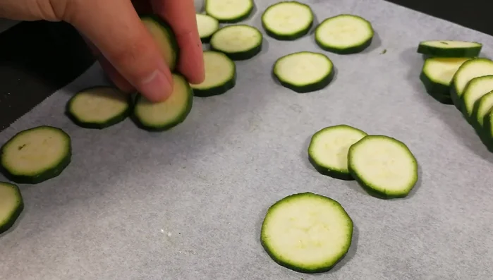 Disporre le rondelle di zucchine su una teglia rivestita con carta forno, in fila indiana, senza sovrapporle.