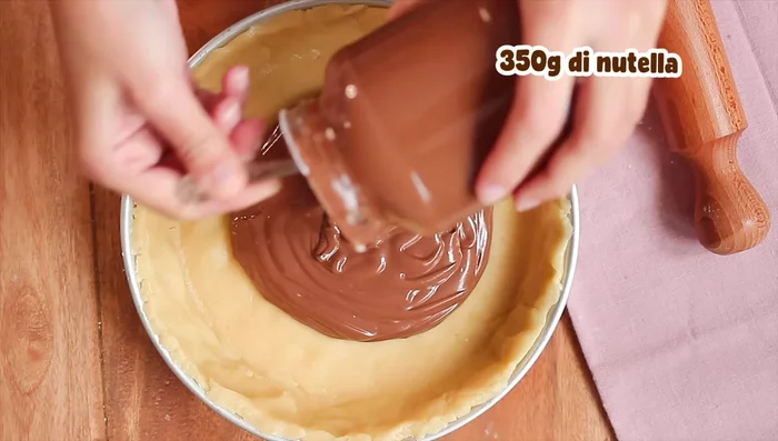 Aggiungere la Nutella precedentemente scaldata a bagnomaria e decorare con la pasta frolla tagliata a strisce.