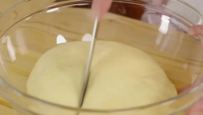 Mettere l'impasto in una ciotola, fare un'incisione a croce, coprire con la pellicola e lasciare lievitare al caldo per circa 2 ore, fino al raddoppio del volume.