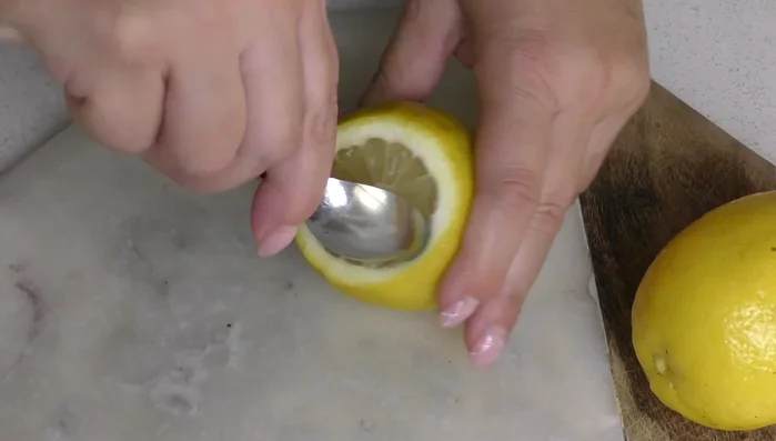 Nel frattempo, pela la scorza di 2 limoni con l'aiuto di un cucchiaino o di un coltellino. Svuoti completamente.