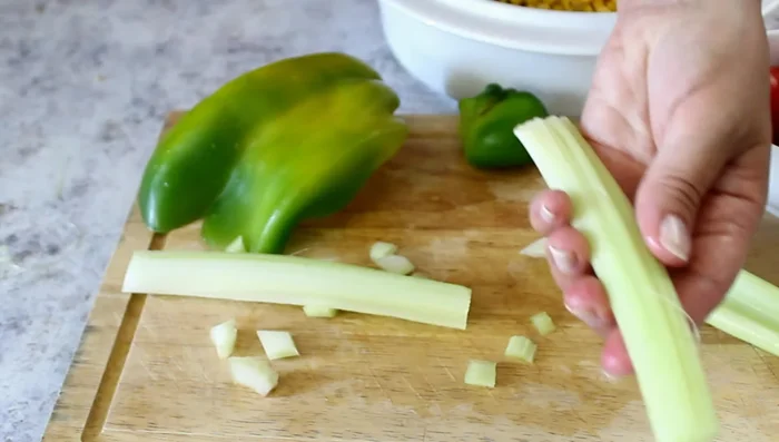 Aggiungere i pomodorini, il sedano (togliendo i filamenti) e il peperone alle lenticchie e al mais nella ciotola.
