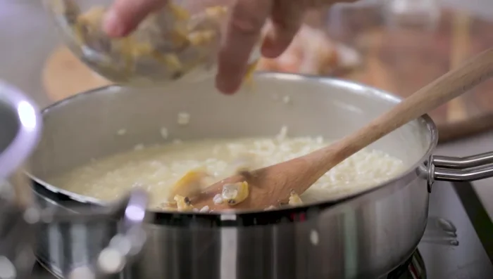 Aggiungere le vongole, i calamari e i gamberi al riso quasi cotto (407.569).