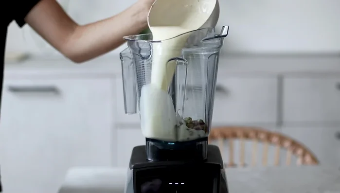 Versare tutti gli ingredienti (pistacchi, latte vegetale, panna di soia e sciroppo d'acero) in un frullatore.