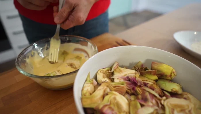 Immergere i carciofi nella pastella e friggerli nell'olio caldo a fiamma media (322.81).
