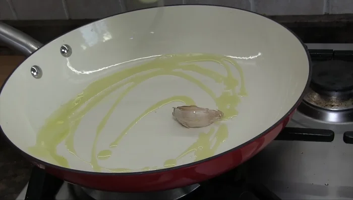 In un'altra padella, preparare un soffritto con olio, uno spicchio d'aglio schiacciato, parte del porro e del prezzemolo (364.72).