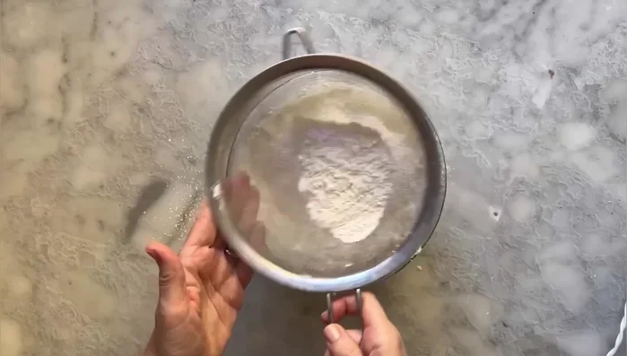 Aggiungere la farina e il lievito, mescolare. Quindi aggiungere il latte caldo, un po' alla volta, amalgamando con una spatola. Si può dare anche un colpo di frusta elettrica.