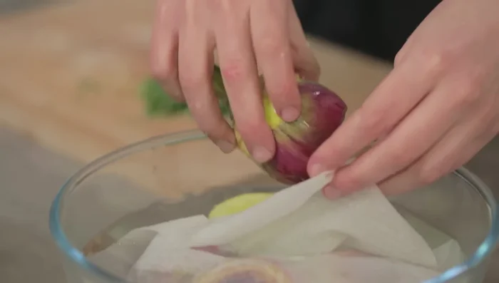 Riempire i carciofi con il trito di mentuccia, sale e pepe. Arrotolare i carciofi nel sale e pepe sul tagliere per insaporirli anche all'esterno.