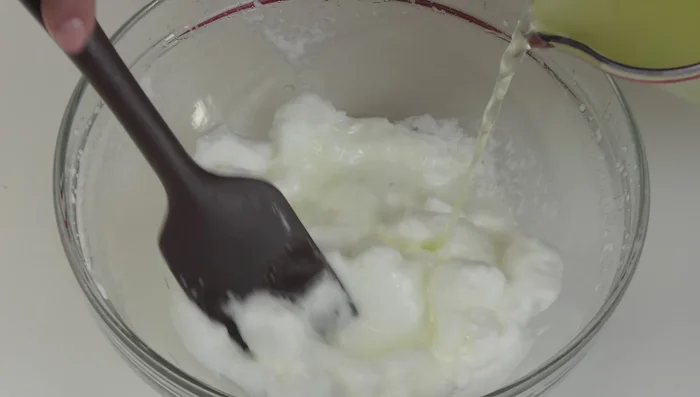 Aggiungere a filo lo sciroppo agli albumi montati, mescolando delicatamente con una spatola in silicone fino ad ottenere un composto liscio e senza grumi.