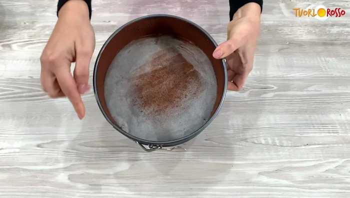 Trasferire il composto in uno stampo a cerniera rivestito di carta forno o imburrato e cosparso di cacao amaro.