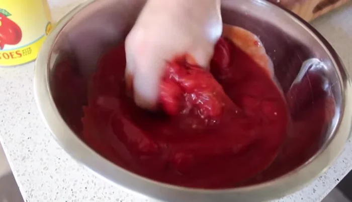 Aggiungere i pomodori San Marzano schiacciati a mano e l'acqua di sciacquatura della lattina. Portare a leggero sobbollire a fuoco medio-alto, poi ridurre la fiamma al minimo e lasciare sobbollire per 4-6 ore, o fino a quando la salsa non si addensa.