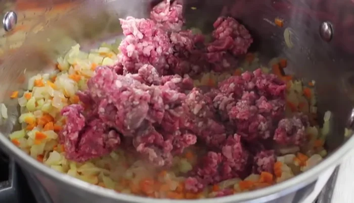 Aggiungere la carne macinata di manzo e cuocere per circa 5 minuti a fuoco medio, mescolando continuamente e sbriciolando la carne con il cucchiaio di legno.
