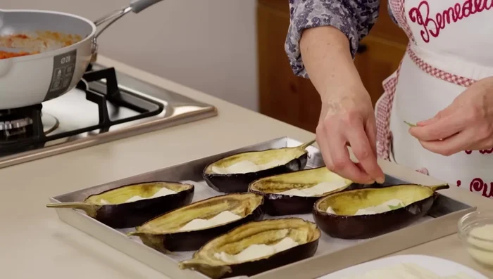 Riempire le melanzane con mozzarella, basilico, il ripieno e formaggio grattugiato. Aggiungere altri strati di mozzarella, basilico e ripieno, concludendo con abbondante formaggio grattugiato.