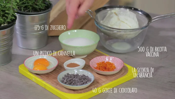 Preparare la crema: nel mixer, unire ricotta ben scolata (almeno 2 ore, meglio se in frigo), zucchero, scorza d'arancia, gocce di cioccolato e cannella. Frullare fino a ottenere una crema liscia.