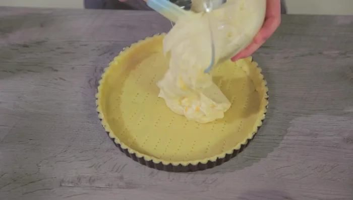Versare la crema di ricotta al centro della base di frolla, livellando con una spatola. Decorare con gocce di cioccolato.