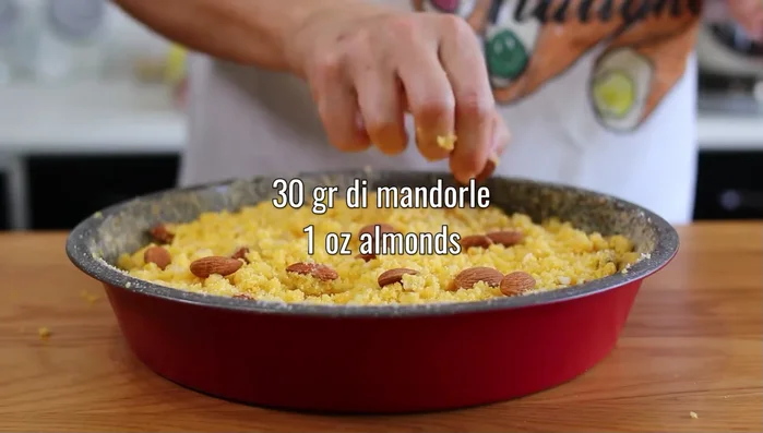 Cospargere la superficie con 30 g di mandorle intere e compattare leggermente la torta.