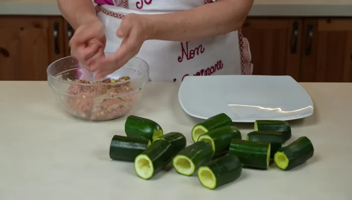 Ricetta 2 (Carne e Sugo): Farciamo le zucchine con il composto. In una padella, soffriggiamo mezza cipolla tritata, aggiungiamo la passata di pomodoro e il sale. Cuociamo per 2-3 minuti.