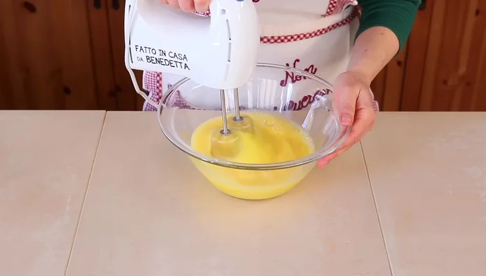 In un'altra ciotola, mescola la farina con il lievito per dolci. Aggiungi gradualmente questo composto agli ingredienti umidi, mescolando delicatamente dal basso verso l'alto per evitare di smontare il composto.