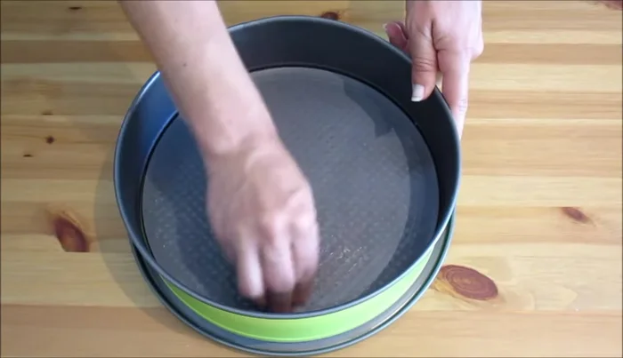 Imburriamo e infariniamo una tortiera cerniera di 24 cm. Inseriamo un disco di carta da forno ritagliato e mettiamo un po' di pangrattato sui bordi.