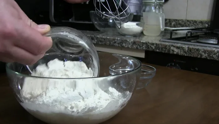 Preparare il lievito madre o il poolish: per il lievito madre (93.7), mescolare 120 g di lievito madre rinfrescato, 180 ml di acqua e 120 g di farina. Lasciar lievitare per 4 ore (135.95). Per il lievito di birra (114.46), sciogliere il lievito in acqua tiepida, aggiungere la farina e formare una pastella. Lasciar lievitare per 2 ore (127.07).