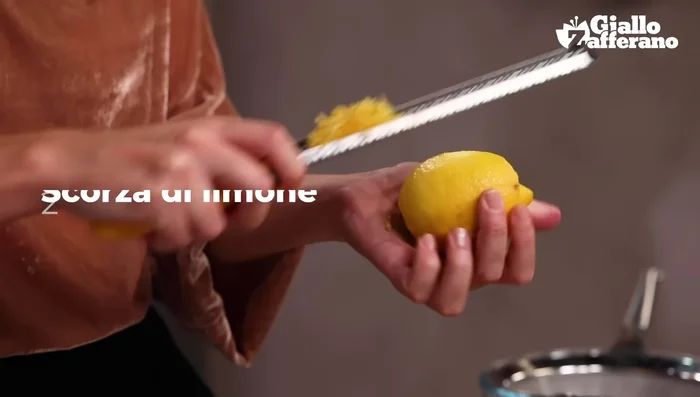 Grattugiare la scorza di limone, tenendo la grattugia rivolta verso l'alto per evitare di grattare la parte bianca amara. Mettere da parte la scorza.