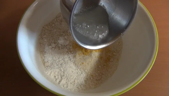 In una ciotola capiente, unire le mandorle tritate, 150 g di zucchero a velo, la buccia di limone grattugiata, l'amido di mais e l'albume leggermente sbattuto. Amalgamare bene.