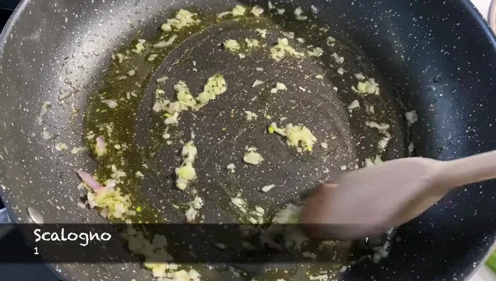 Preparare il condimento: rosolare scalogno (o cipolla) in olio, aggiungere i pomodorini a metà e cuocere per pochi minuti.