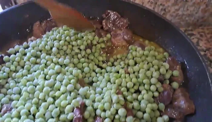 Dopo circa mezz'ora, aggiungere i piselli (anche surgelati) e continuare la cottura a fuoco lento fino a quando i piselli sono cotti e il sughetto si è addensato.