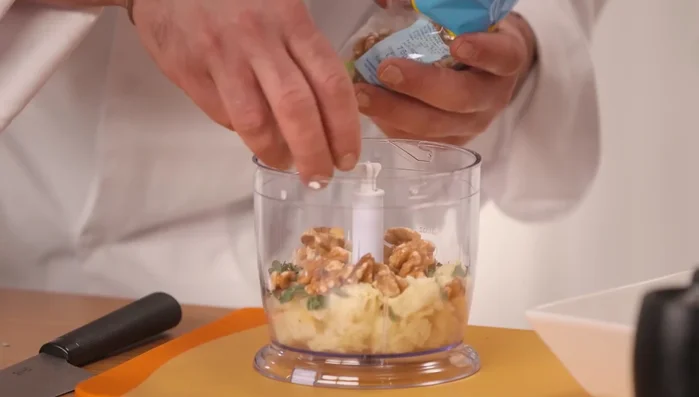 Preparare il pesto di noci: nel frullatore, unire noci, pinoli, maggiorana, un filo d'olio.