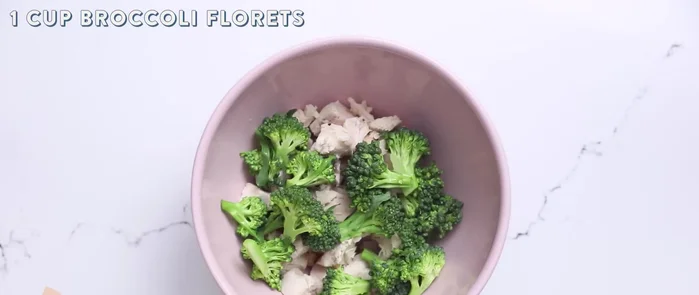 In una ciotola, unisci il pollo, i broccoli tritati, l'aglio schiacciato, il sale, la salsa Alfredo, il pepe e il parmigiano grattugiato.