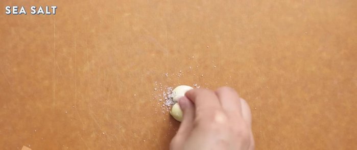 Schiaccia e sbuccia 2 spicchi d'aglio. Aggiungi sale marino e schiaccia bene per estrarre l'umidità e intensificare il sapore.