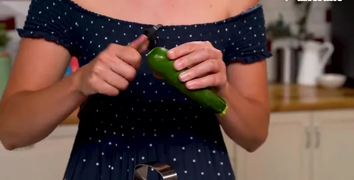 Lessare i fusilli. Grattugiare le zucchine crude. Preparare il pesto di zucchine frullando le zucchine grattugiate con pinoli, basilico, parmigiano, pecorino e olio.